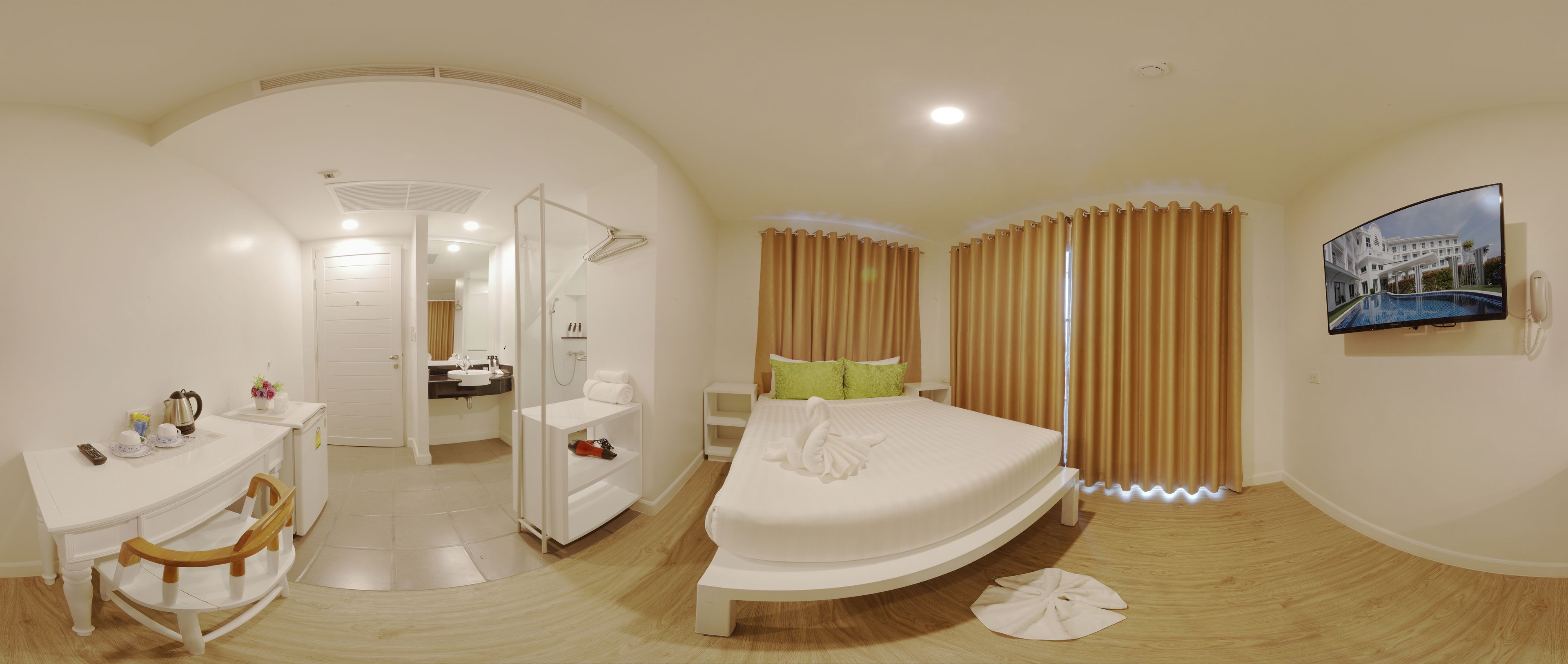 A hotel room with a bed, a desk, a mirror, and a bathroom.