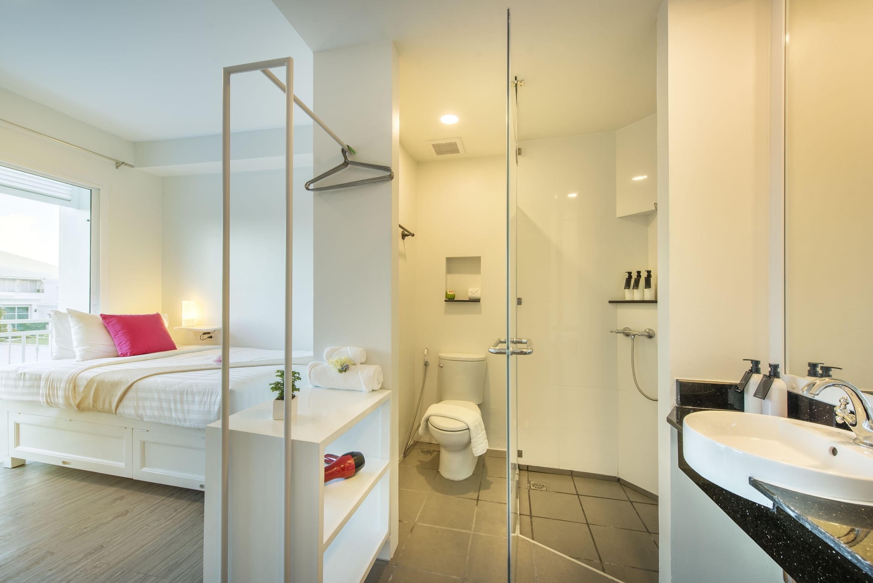 A modern bathroom with a glass shower enclosure, a white toilet, and a sink with a black countertop.
