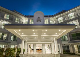 Un hotel de varios pisos con una entrada central, ventanas grandes y un emblema decorativo sobre la entrada.