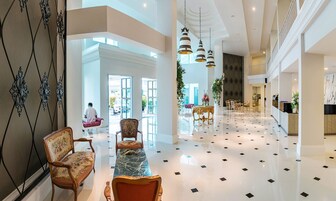 Un vestíbulo amplio con suelo de mármol, muebles elegantes y un candelabro moderno.