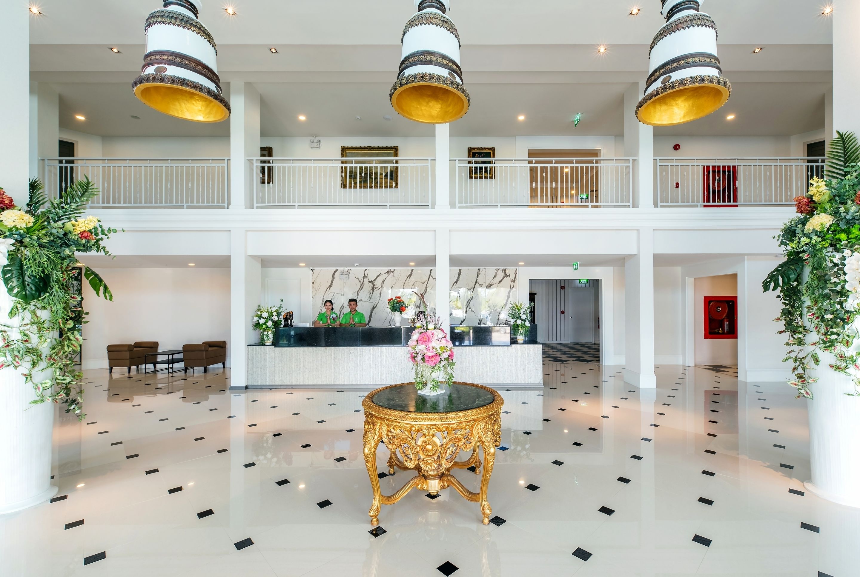 A spacious lobby with a central round table, two balconies, and a reception desk.