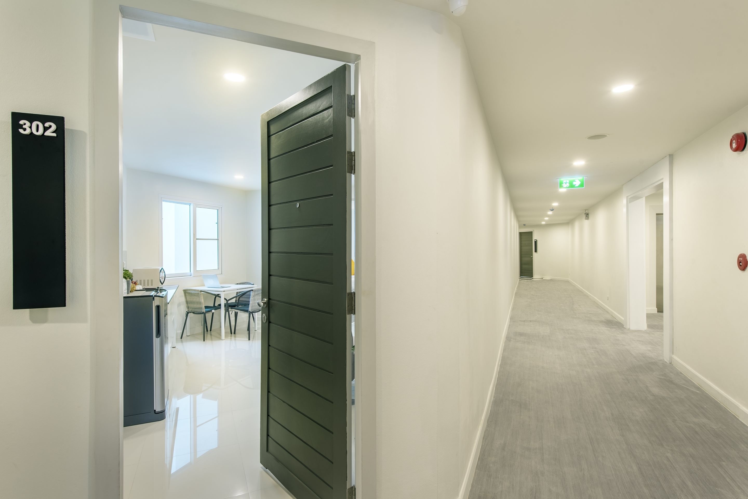 A hallway with a door marked 302, leading to a room with a desk and chairs.