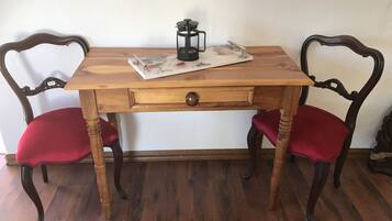 A wooden table with a drawer, two red upholstered chairs, and a decorative item on the table.