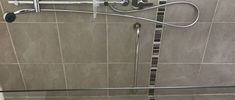 A shower with a handheld showerhead and a fixed showerhead, both mounted on a tiled wall.