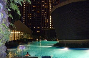 A nighttime swimming pool area with a 'No Diving' sign, surrounded by tall buildings and illuminated windows. - Go Daily service (Kuala Lumpur)