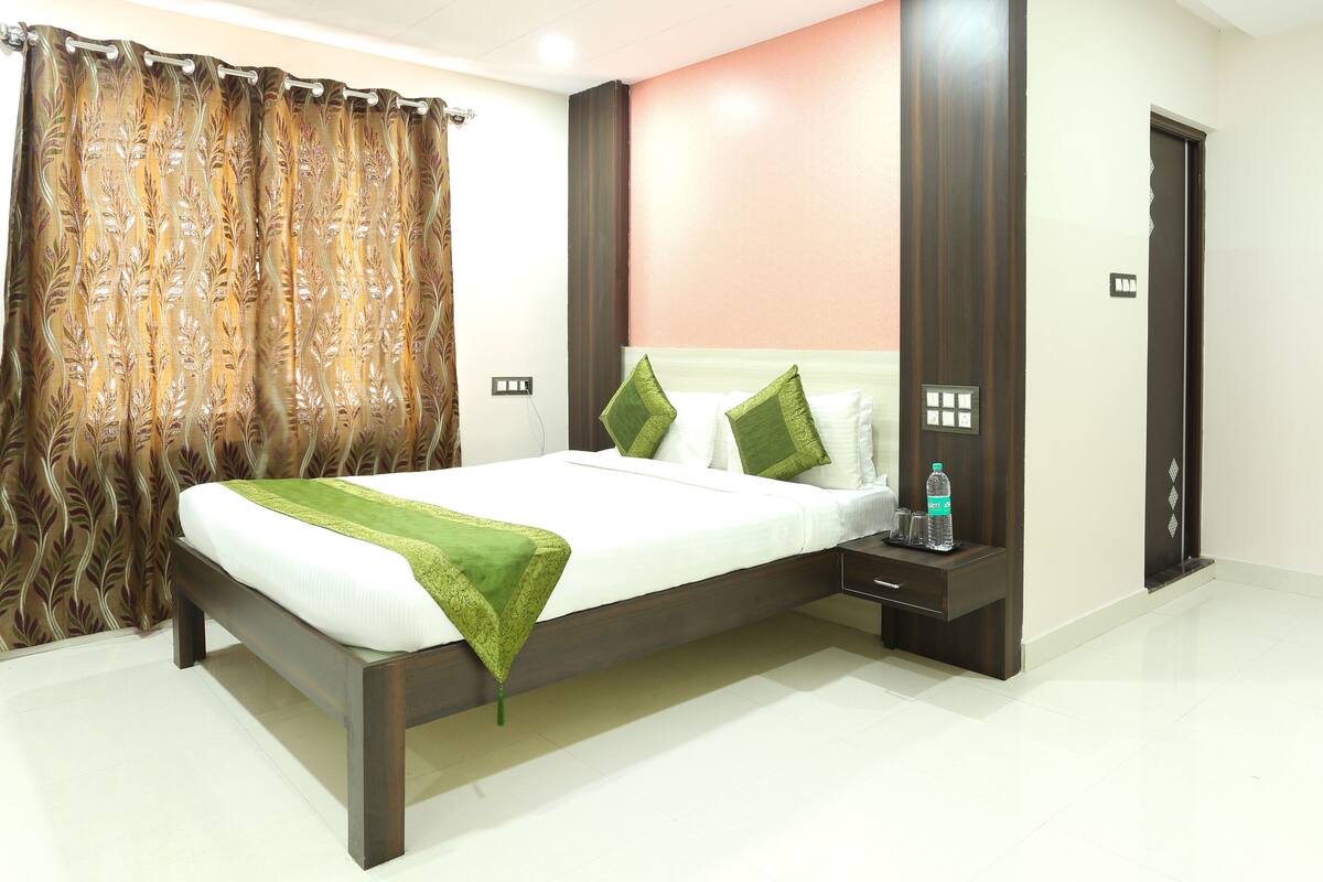 A modern hotel room with a bed, a nightstand, a water bottle, and a door.