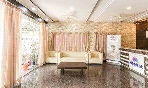A reception area with a stone wall, two sofas, a coffee table, and a banner for Habitat Suites & Rooms. - Treebo Habitat Suites and Rooms (Bengaluru)