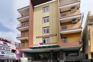Ein mehrstöckiges Gebäude mit Balkonen, Klimaanlagen und der Beschilderung 'Habitat' und 'Kanhaiya Towers'.