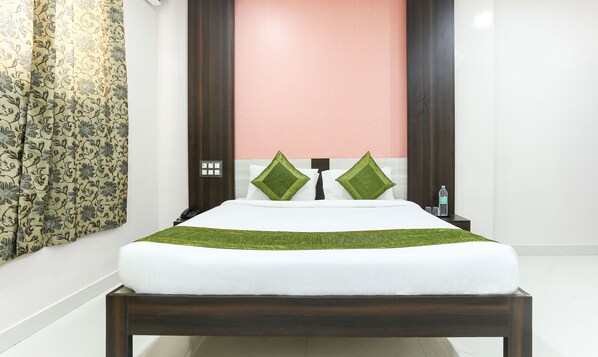 A neatly made bed with a white mattress and green bedspread, a wooden headboard, and two green pillows. - Treebo Habitat Suites and Rooms (Bengaluru)