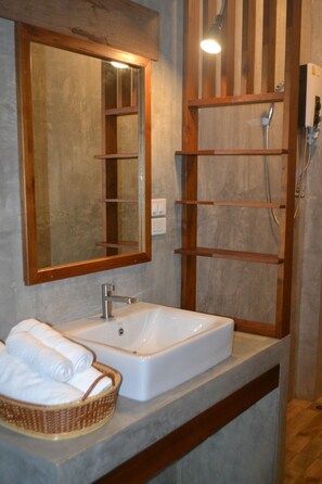 A bathroom with a large mirror, a white sink, and a wooden shelf. - Le Cocotier Resort (Mae Taeng)