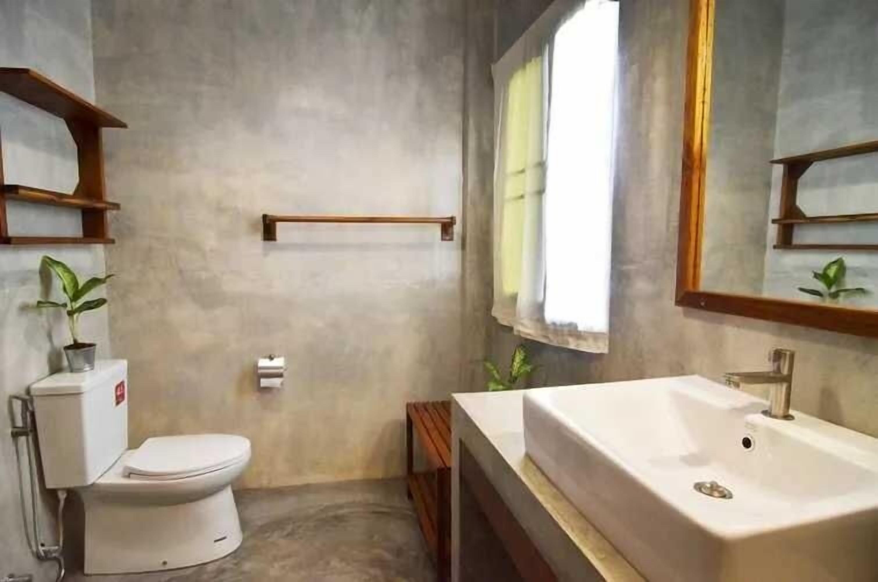 A bathroom with a toilet, sink, and wooden shelves.