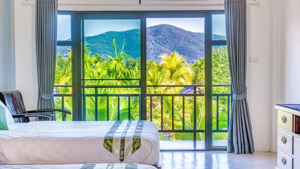 A bedroom with a large window, a bed, a chair, and a dresser. - Le Cocotier Resort (Mae Taeng)