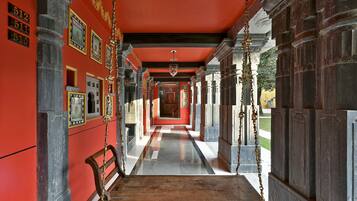 A corridor with a red wall, numbered plaques, and a wooden bench.
