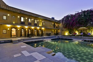 A courtyard with a pool, outdoor seating, and a building with traditional architecture.
