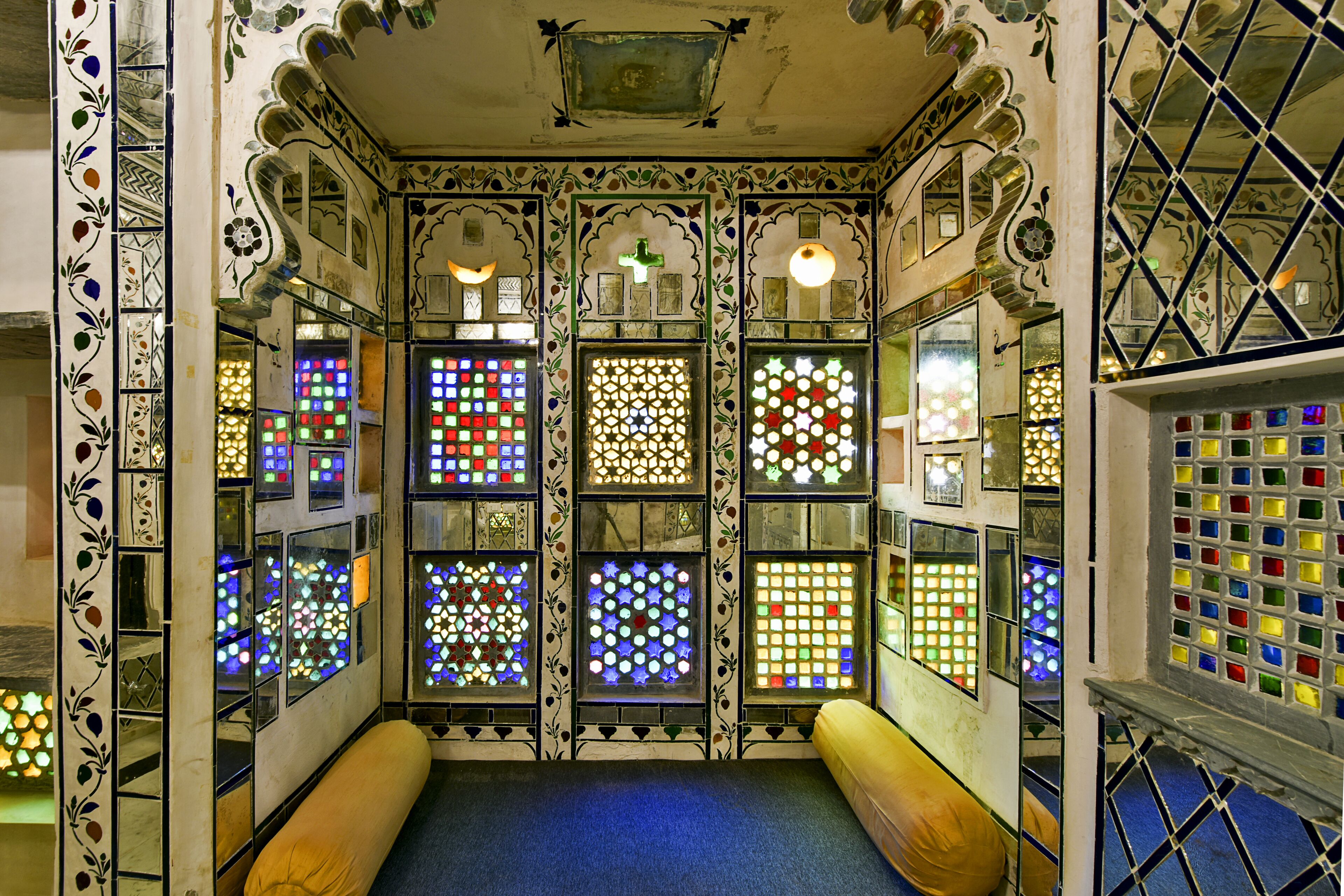 A room with multiple stained glass windows and intricate wall designs.