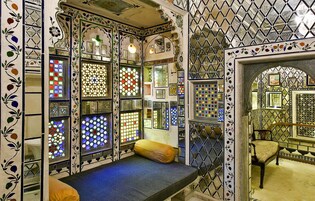 A room with a bench, decorative glass panels, and a wooden chair.