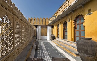 A corridor with ornate lattice work, a bench, and a large vase.