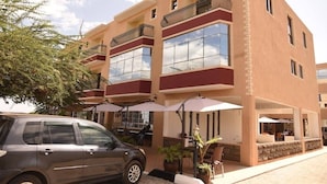A multi-story hotel with balconies, outdoor seating, and a car parked in front. - Mara Frontier Hotel (Narok)