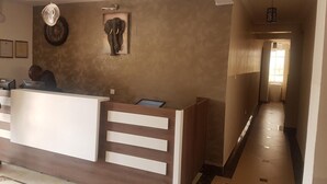 A reception area with a wooden reception desk, a wall-mounted elephant sculpture, and framed pictures. - Mara Frontier Hotel (Narok)