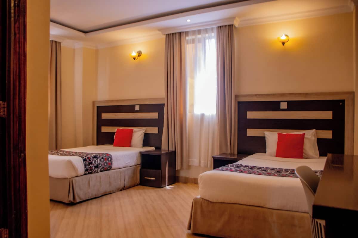 Une chambre d’hôtel avec deux lits, un bureau et une table de chevet.