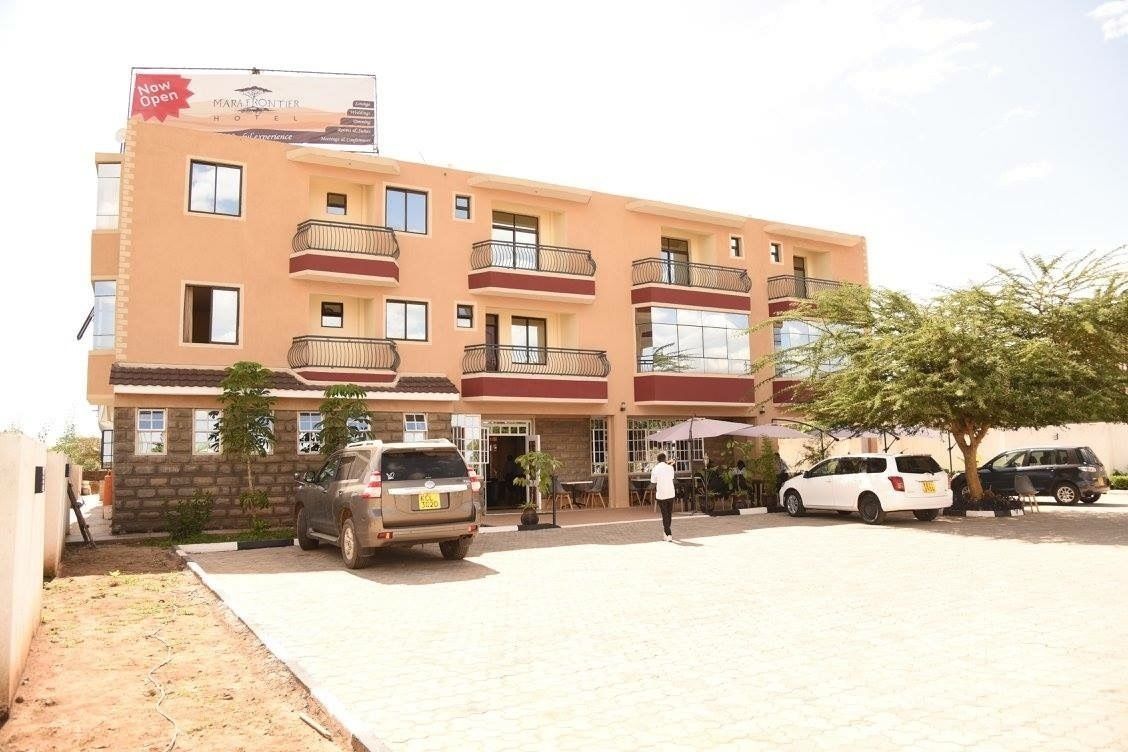 A multi-story hotel with balconies, a paved driveway, and outdoor seating.