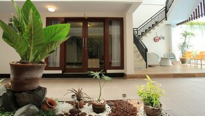 A spacious indoor area with a staircase, potted plants, and a seating area. - Legian Village Residence (Legian)