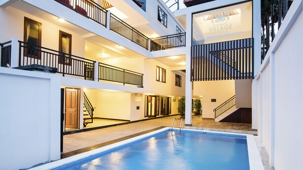 A multi-level indoor swimming pool with balconies and a sign for "LEGIAN VILLAGE". - Legian Village Residence (Legian)