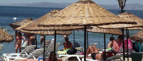 Na praia, guarda-sóis, toalhas de praia