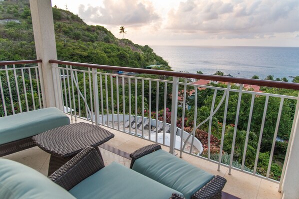A balcony with wicker furniture and a view of the ocean.