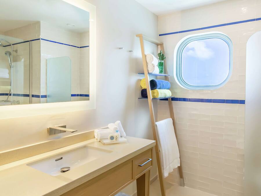 A bathroom with a large mirror, a sink, a towel rack, and a window.