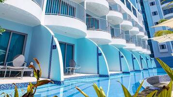 Un hôtel moderne doté de nombreux balcons, d’une piscine et de plantes tropicales.