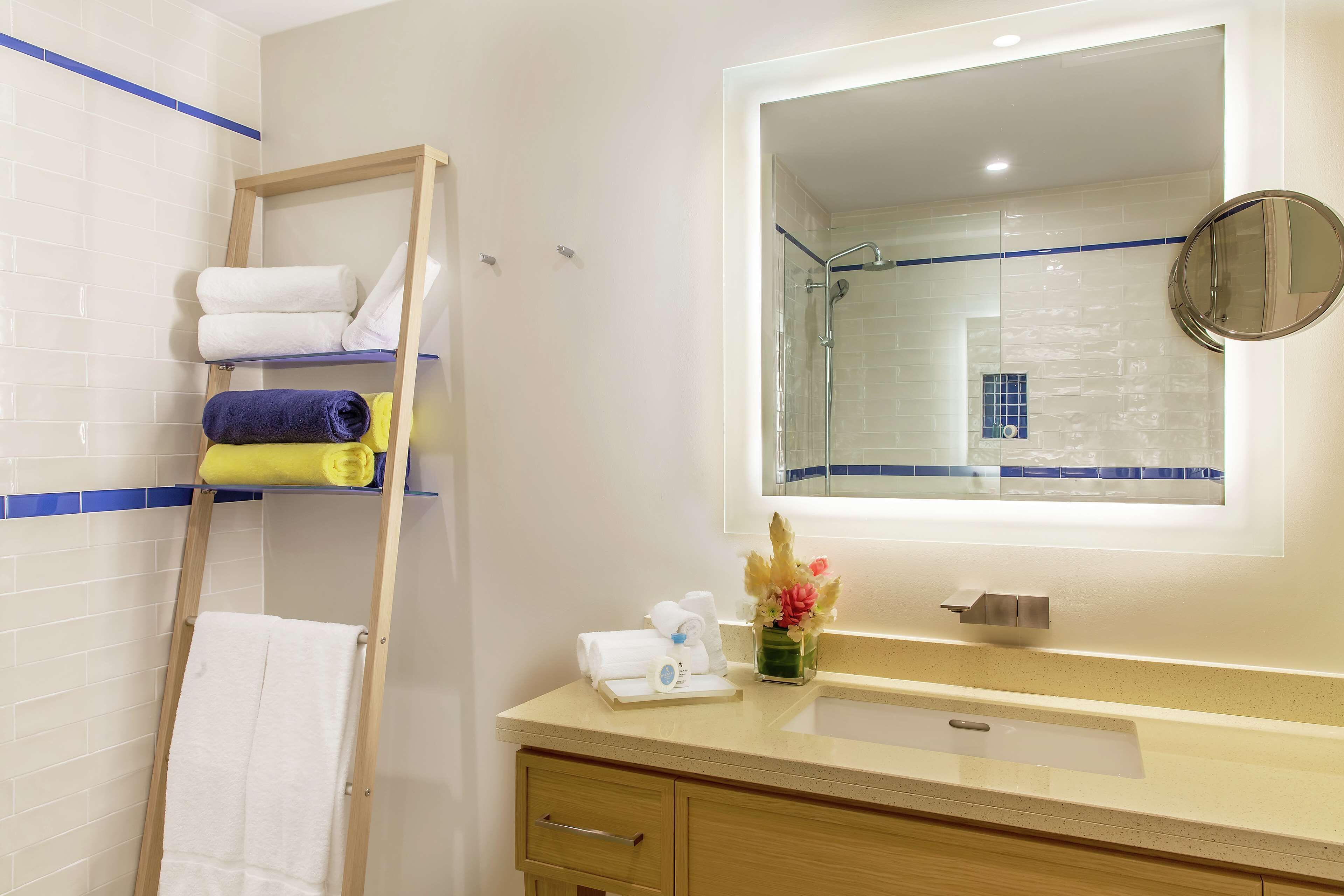A bathroom with a wooden ladder, a sink, a mirror, and a towel rack.