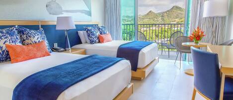 A hotel room with two beds, a balcony with a view, and a dining area with a table and chairs.