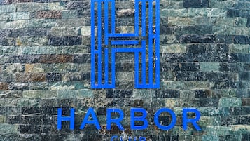 Logotipo com as letras 'H' e 'H' formando um 'H' estilizado sobre um fundo de parede de pedra texturizada.