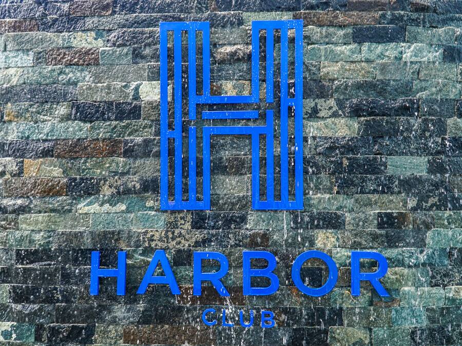 Logotipo com as letras 'H' e 'H' formando um 'H' estilizado sobre um fundo de parede de pedra texturizada.
