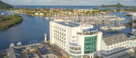 Puerto deportivo con varias embarcaciones, un edificio blanco con una sección de vidrio curvada y una torre del reloj.