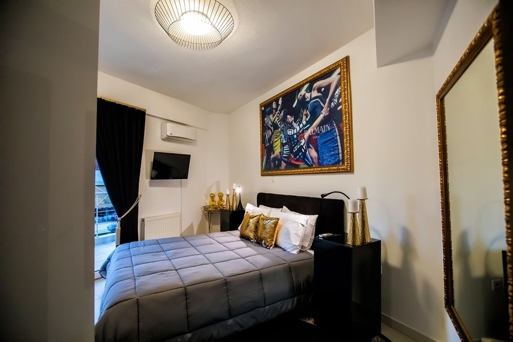 Una camera da letto con un letto, un grande specchio, un quadro e una TV appesa al muro.