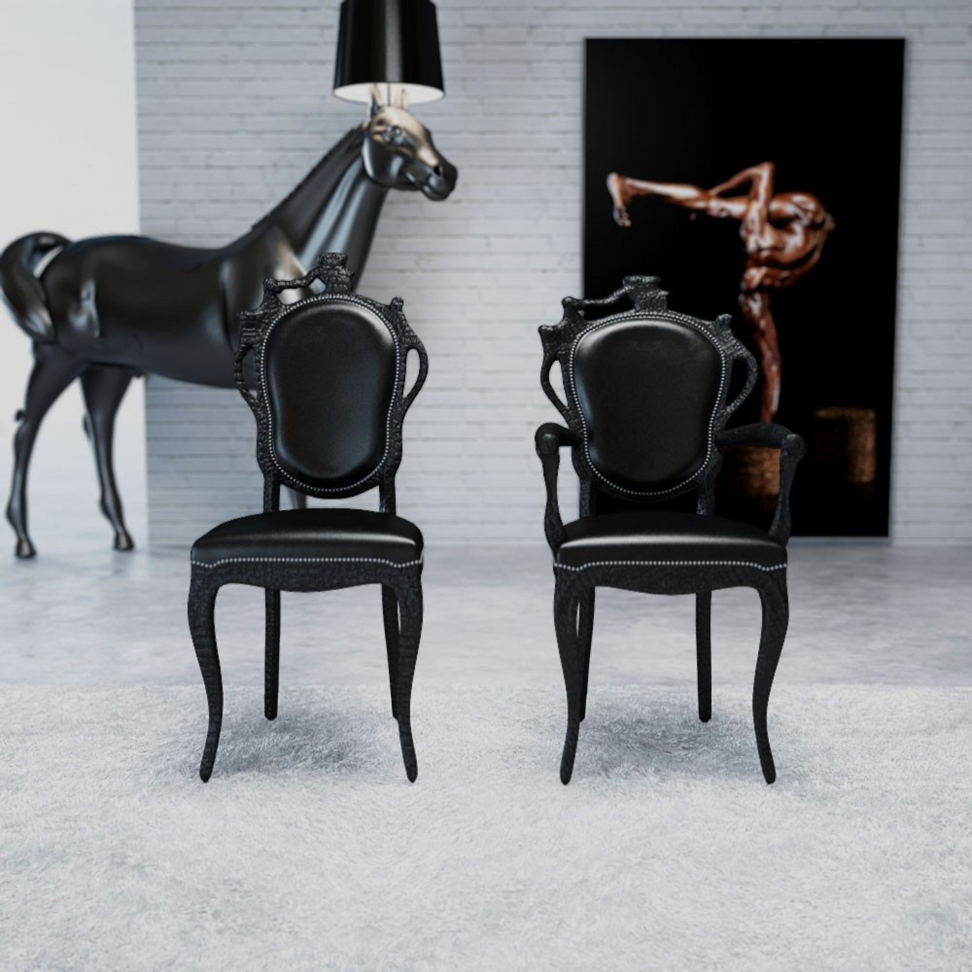 Two black chairs with ornate backs and a black lamp above them.