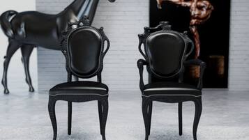 Two black chairs with ornate backs and a black lamp above them.