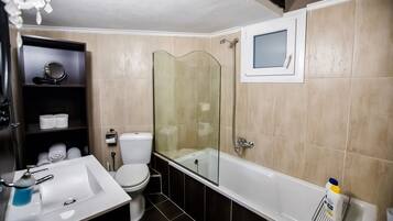 Une salle de bain avec une douche à parois de verre, un lavabo blanc, des toilettes et une étagère contenant des articles de toilette.