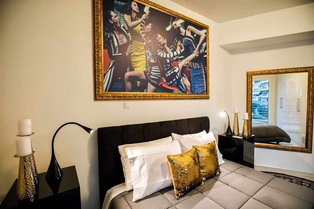 Ein Schlafzimmer mit einem großen Bett, einem gerahmten Kunstwerk darüber, einem Nachttisch mit Lampe und einem Spiegel an der Wand.