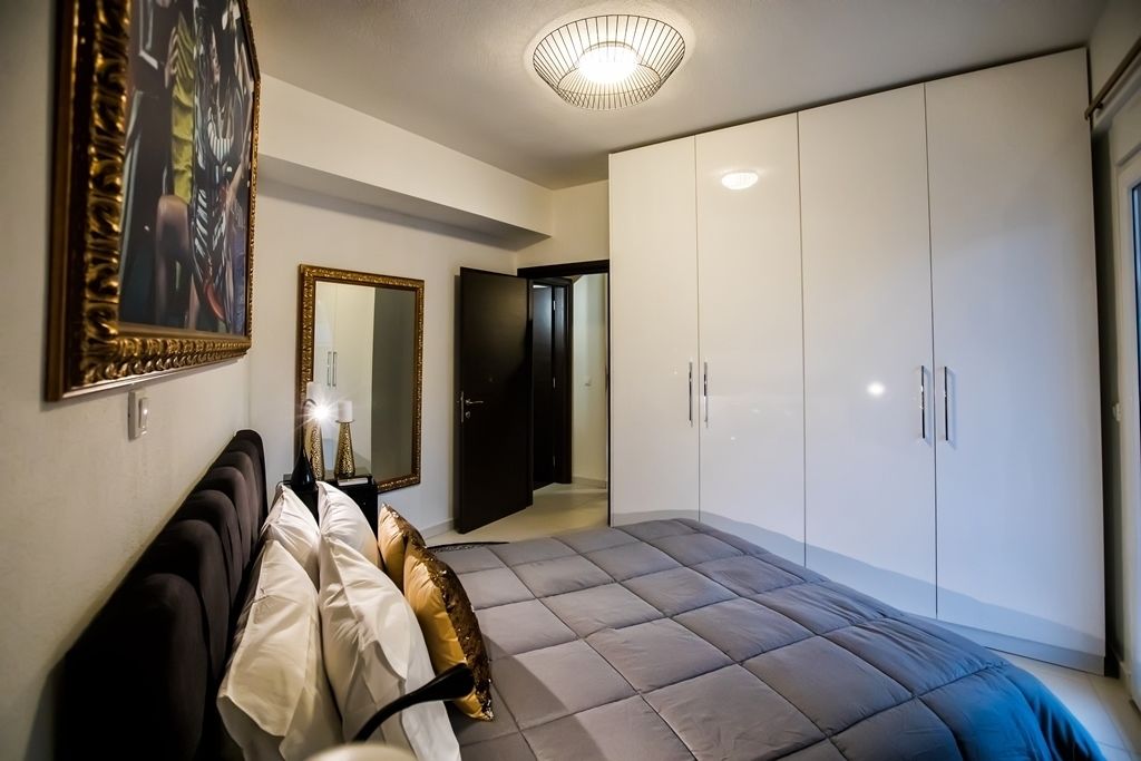A bedroom with a large bed, a wardrobe, a mirror, and a ceiling light fixture.