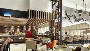A modern dining area with a central island, seating arrangements, and a decorative wall. - Novotel Karawang (Karawang)