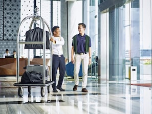 A modern lobby with a luggage cart, a reception desk, and a glass wall with reflections. - Novotel Karawang (Karawang)