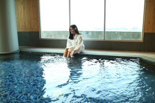 A person sitting in a pool with a view of a building through large windows.