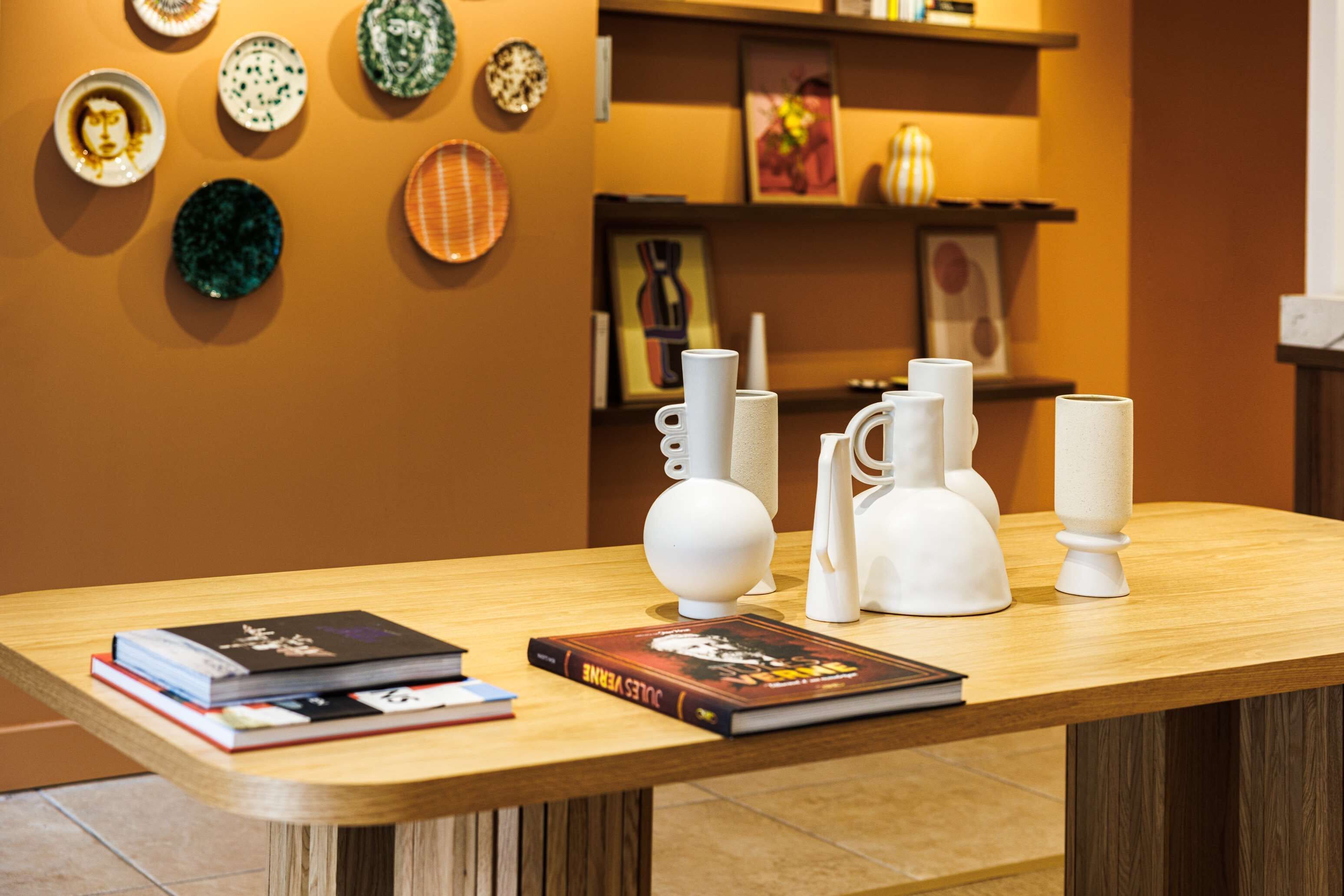 A wooden table with books and white ceramic vases.