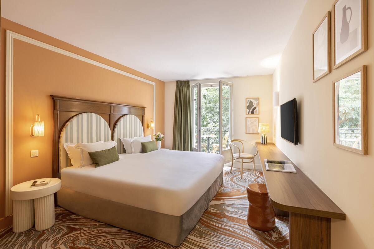 Ein Hotelzimmer mit einem großen Bett, einem Schreibtisch, einem Stuhl und einem Fernseher.