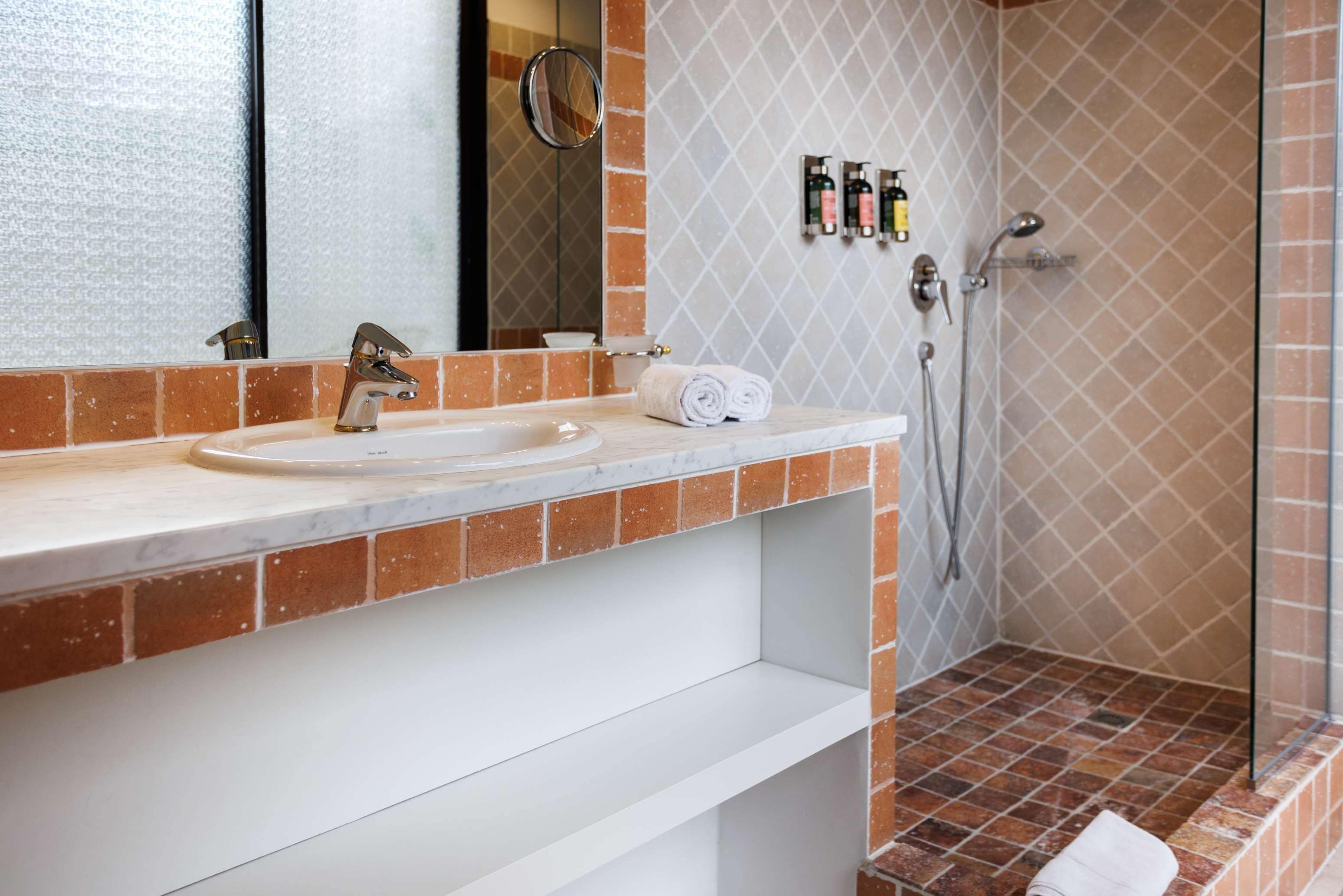 Baño con lavamanos, espejo y ducha.