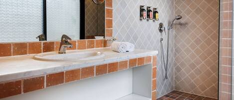 Baño con lavamanos, espejo y ducha.