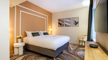 A hotel room with a bed, bedside tables, a TV, and artwork on the wall.